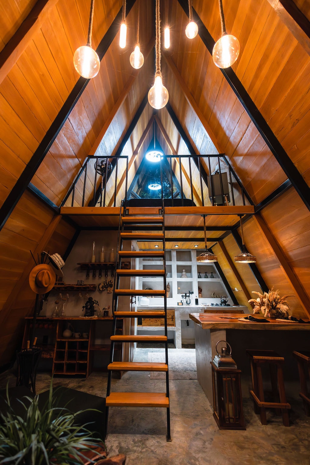 A-frame cabin interior with warm wood tones and pendant lighting at Casa Tattva