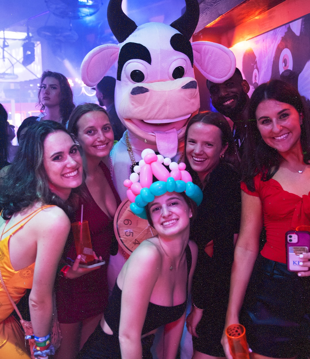 Group of friends posing with the La Vaquita cow mascot inside the club in Cancún
