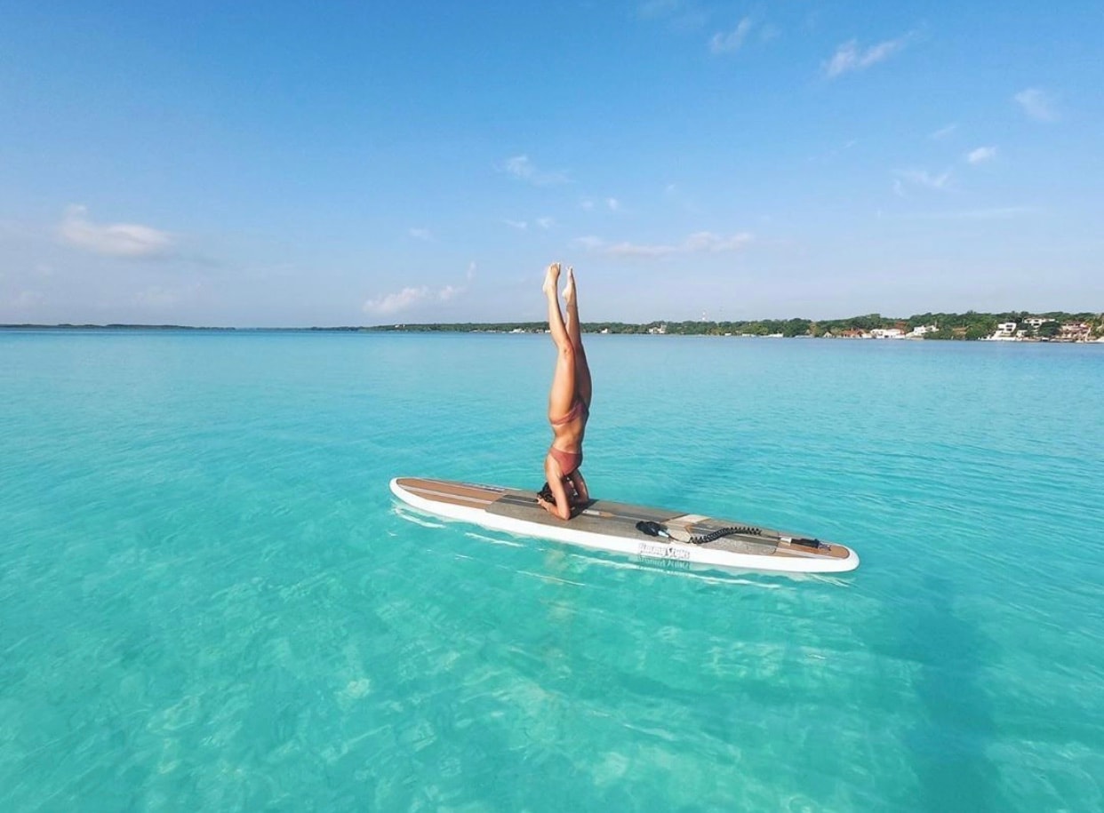Paddleboard headstand on the crystal-clear turquoise waters of Bacalar Lagoon