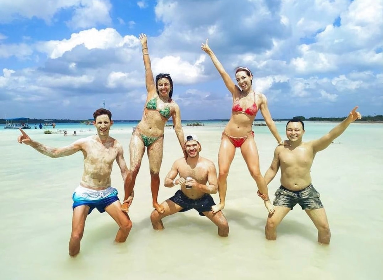 Happy group of travellers covered in mud on the Bacalar sandbank