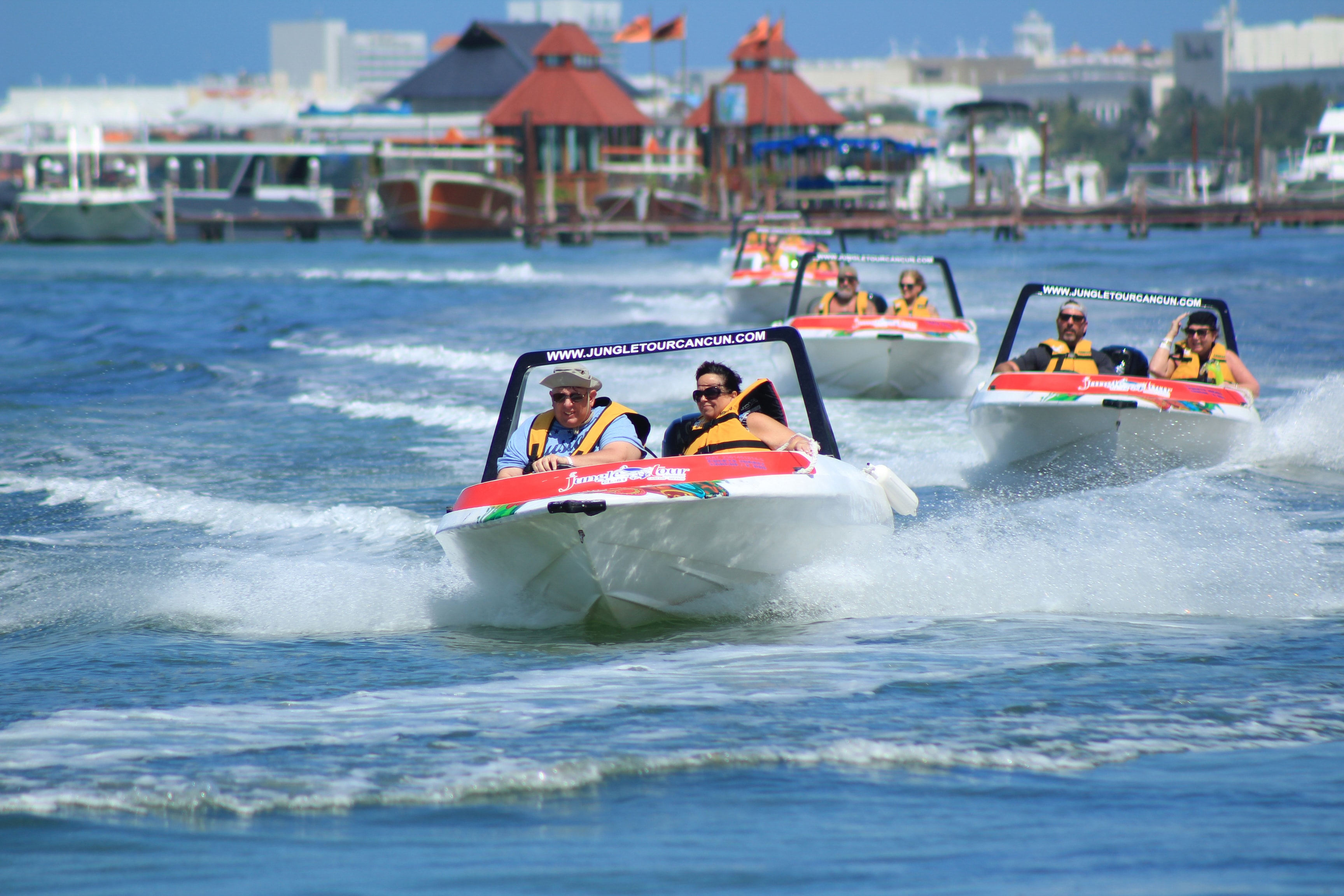 Fleet of Jungle Tour speedboats racing across the Cancun lagoon with the Hotel Zone behind