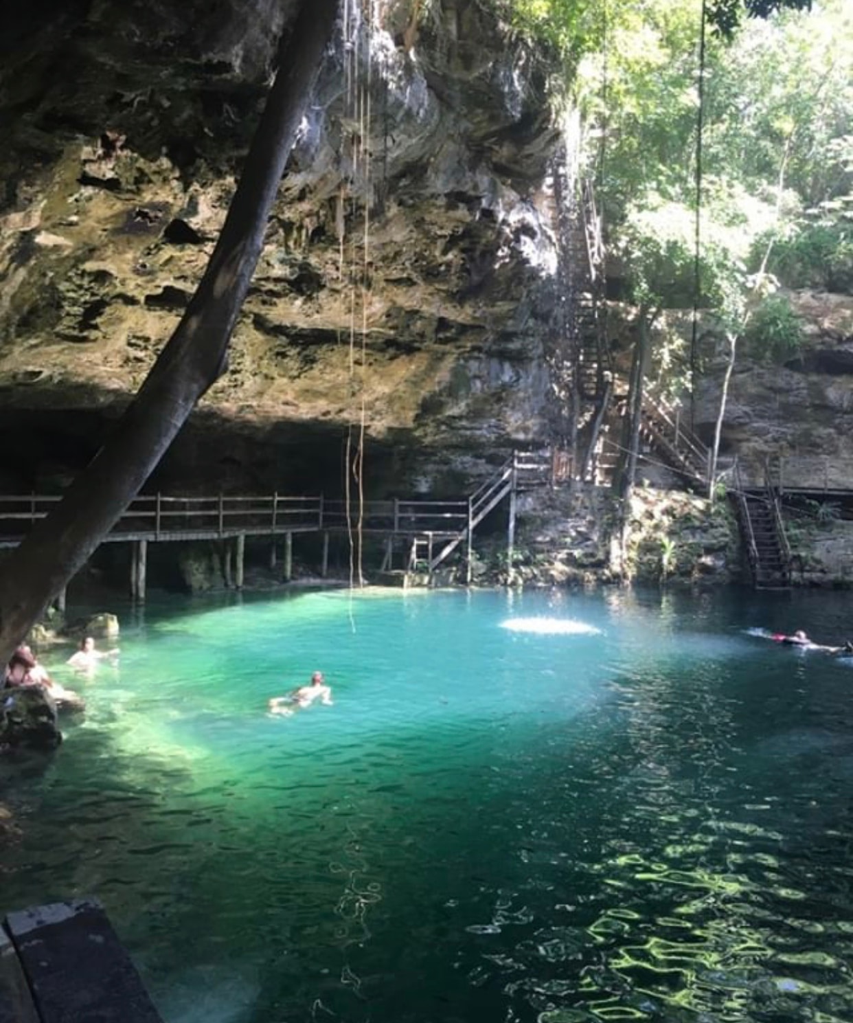 Swimmers enjoying the emerald-green waters of a cave cenote near Ek Balam