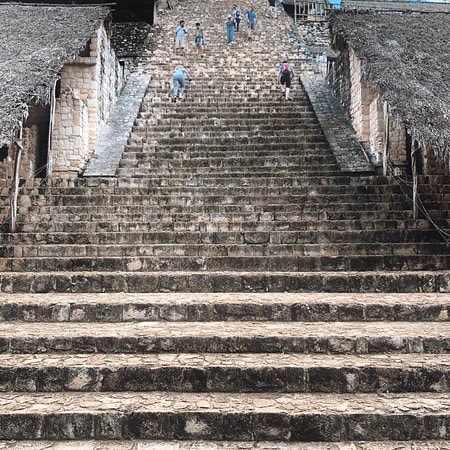 Visitors climbing the steep stone staircase of the Ek Balam pyramid to the summit