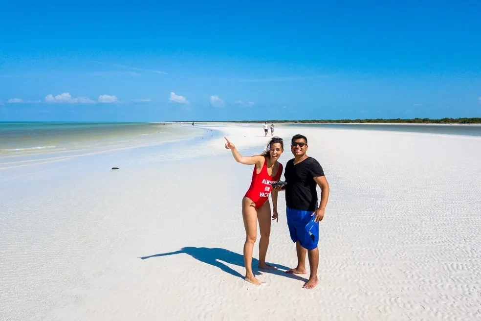 Couple posing on the vast white sandbar of Holbox Island with turquoise water stretching to the horizon