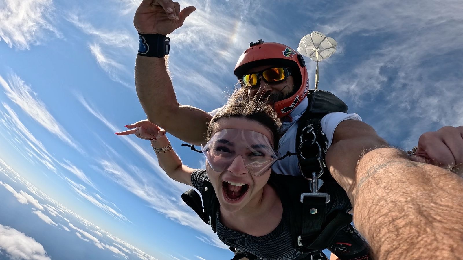 Tandem skydiver and instructor in freefall with a wide grin over the Caribbean coast