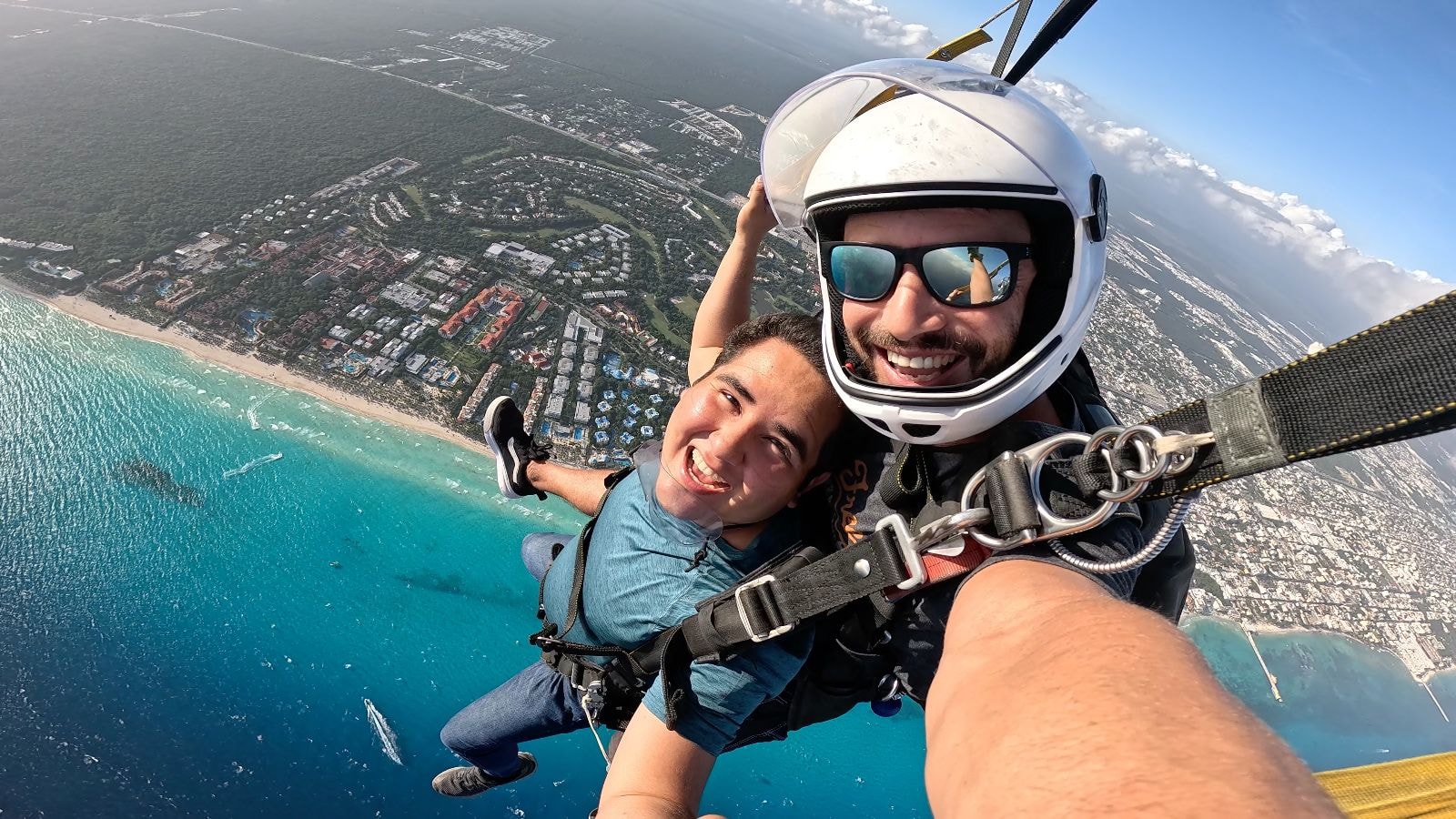 Tandem pair under a blue canopy gliding over the turquoise Caribbean coastline