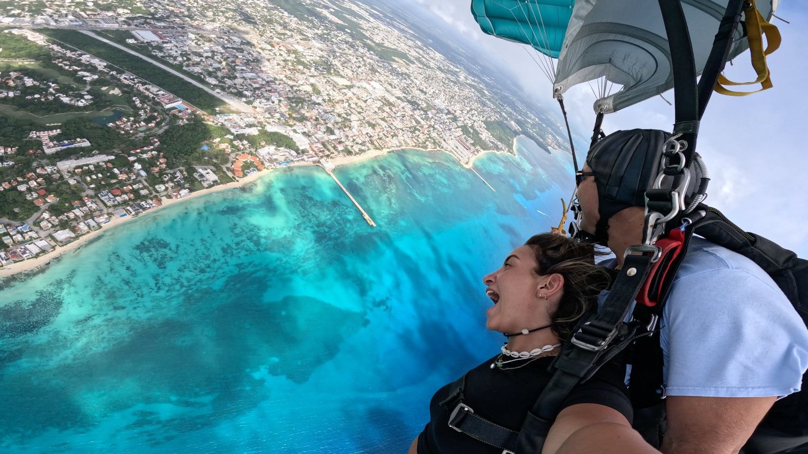 Tandem skydiver and instructor in freefall over the Riviera Maya with turquoise water below