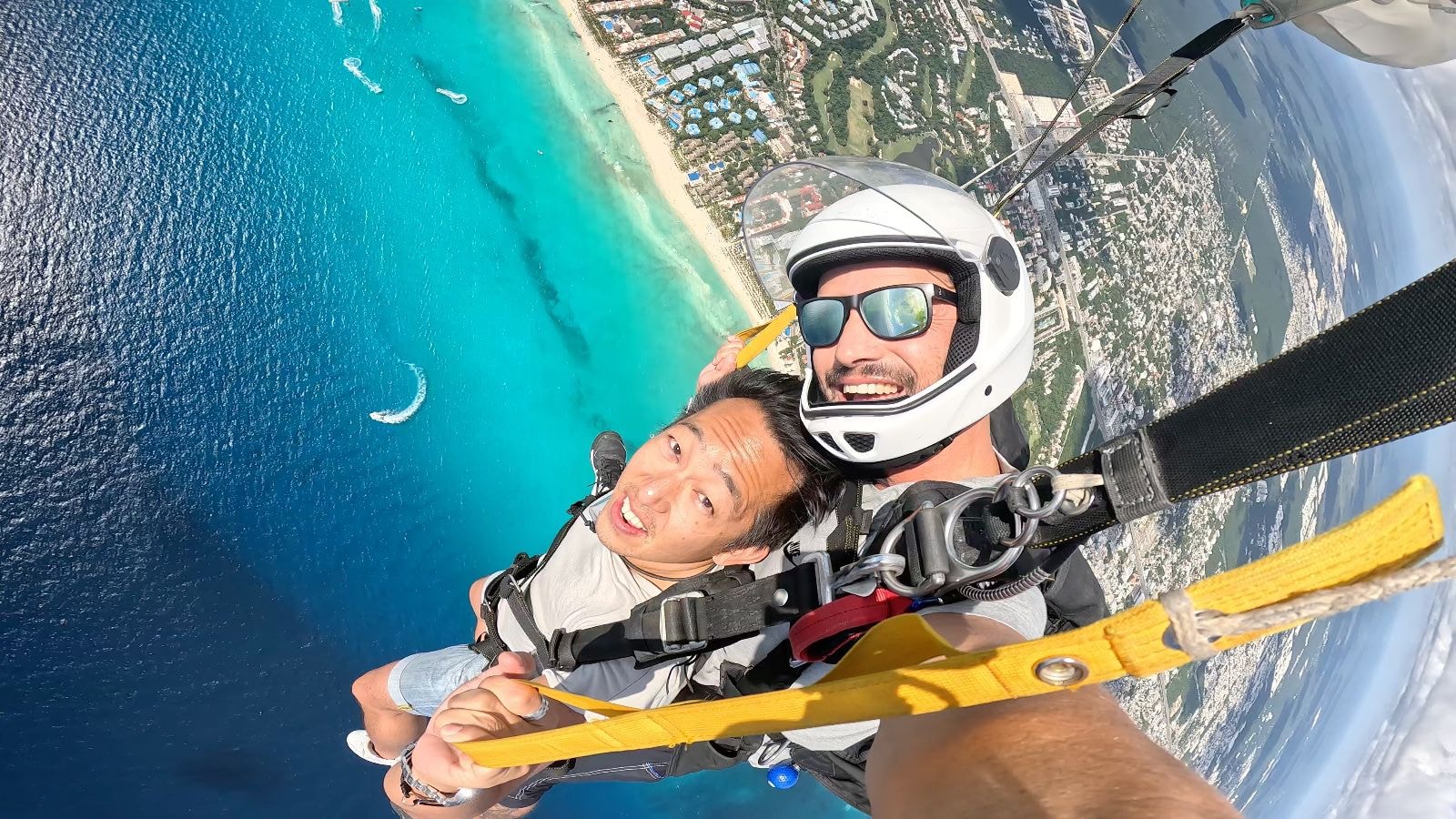 Woman screaming with joy in freefall over the Caribbean with parachute visible above