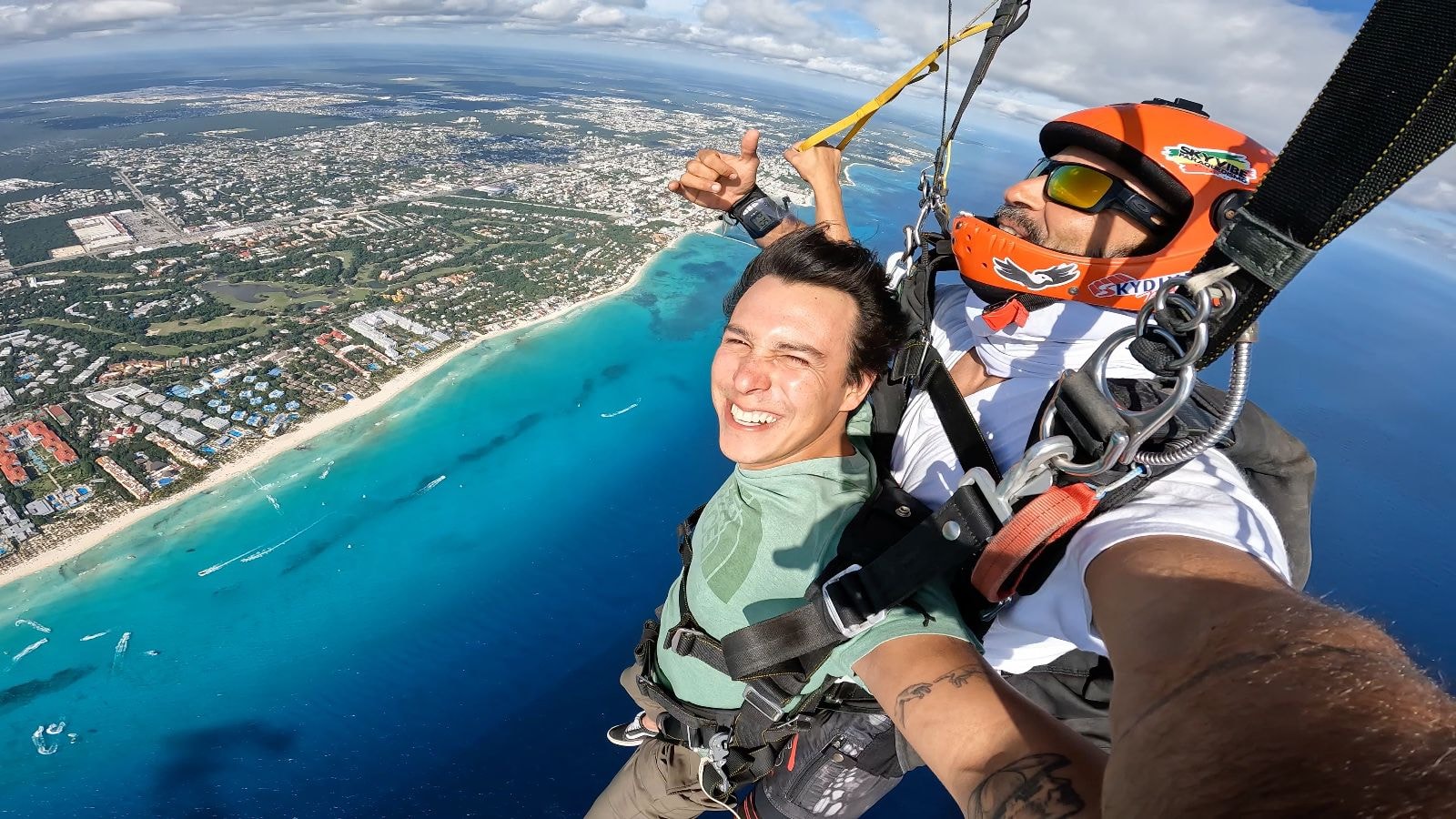 Tandem pair in freefall over the Caribbean with the Riviera Maya coastline in the background