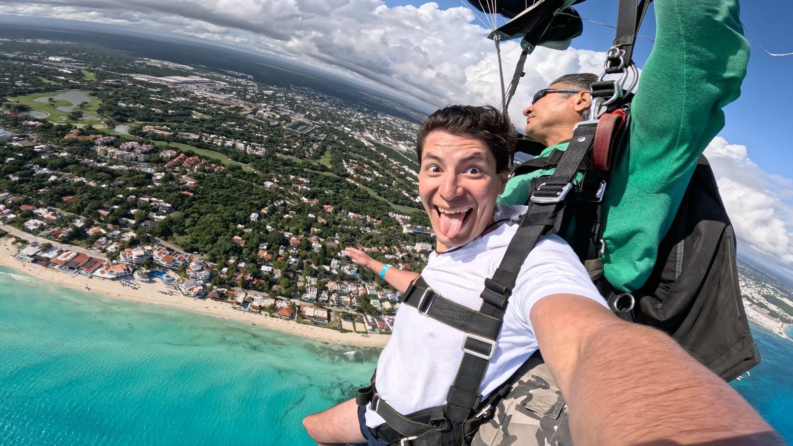 Man under parachute gliding over the turquoise Caribbean with Playa del Carmen below