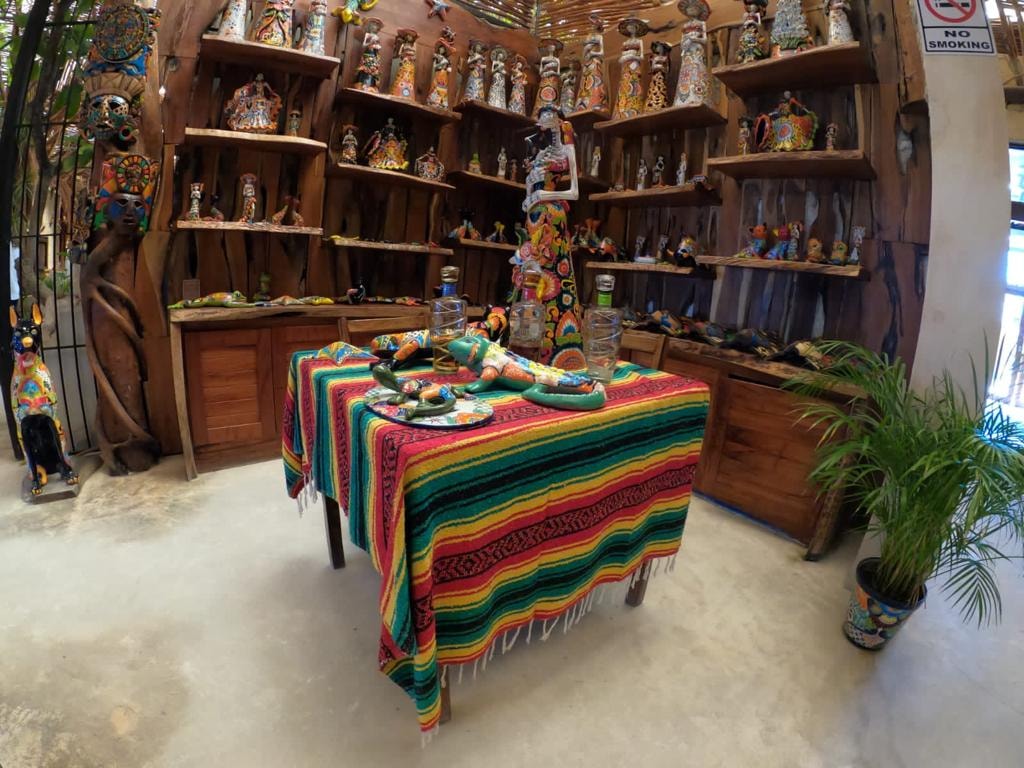 Colourful Mexican artisan shop in Puerto Morelos with hand-painted figurines, Huichol art and a striped serape tablecloth