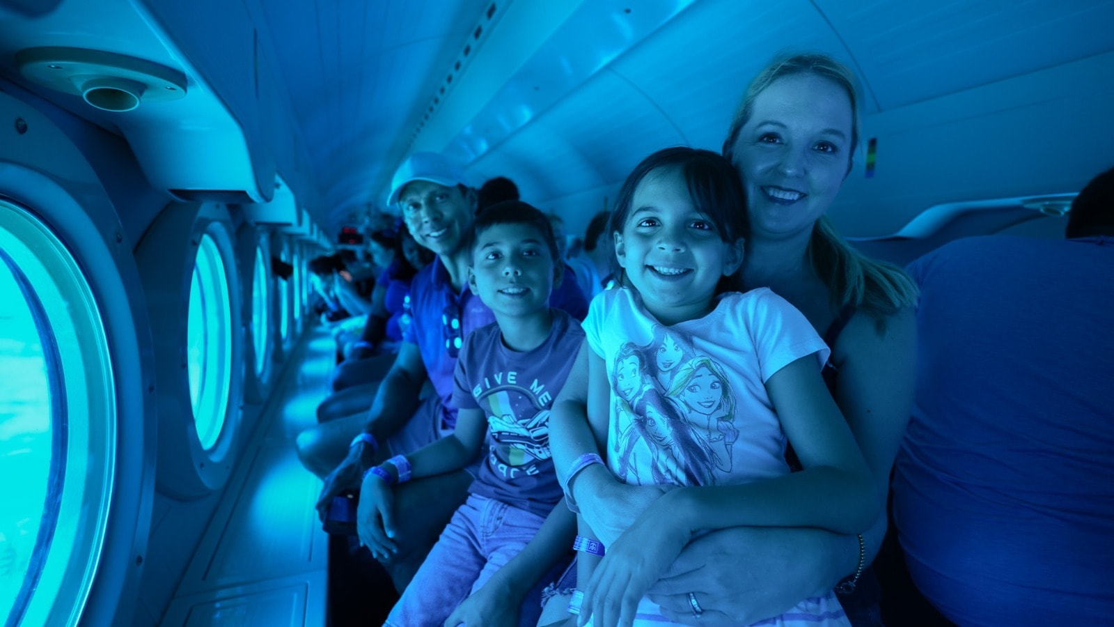 Happy family with two children smiling inside the air-conditioned cabin of the Atlantis XII submarine in Cozumel