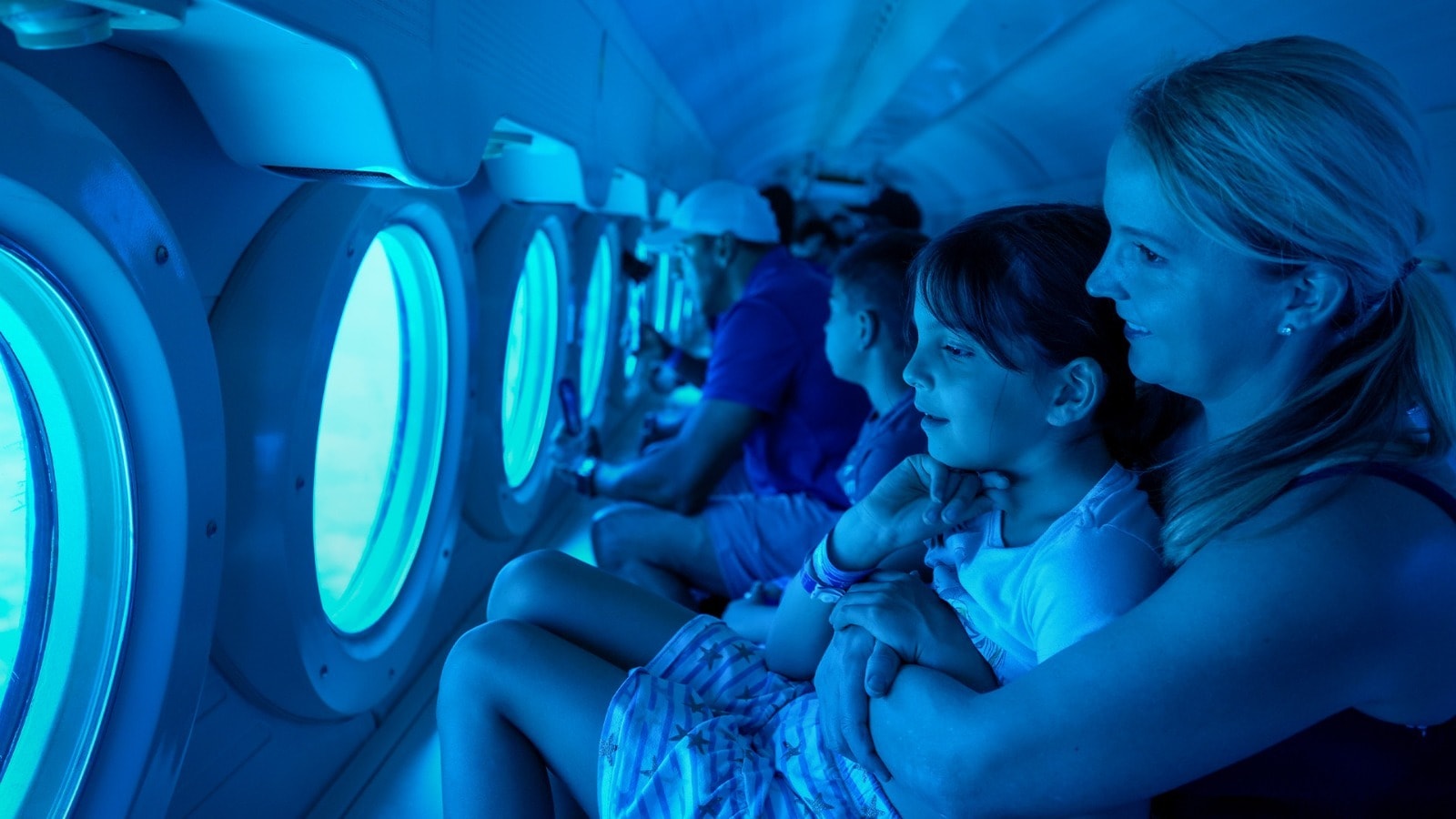 Mother and child gazing through the oval portholes at the coral reef and tropical fish during the Atlantis submarine dive in Cozumel
