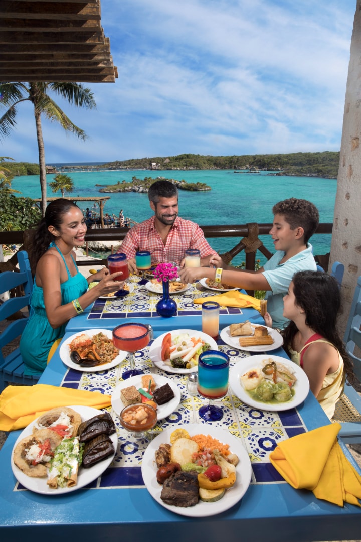 Family dining at a beachfront restaurant with turquoise water views at Xel-Há