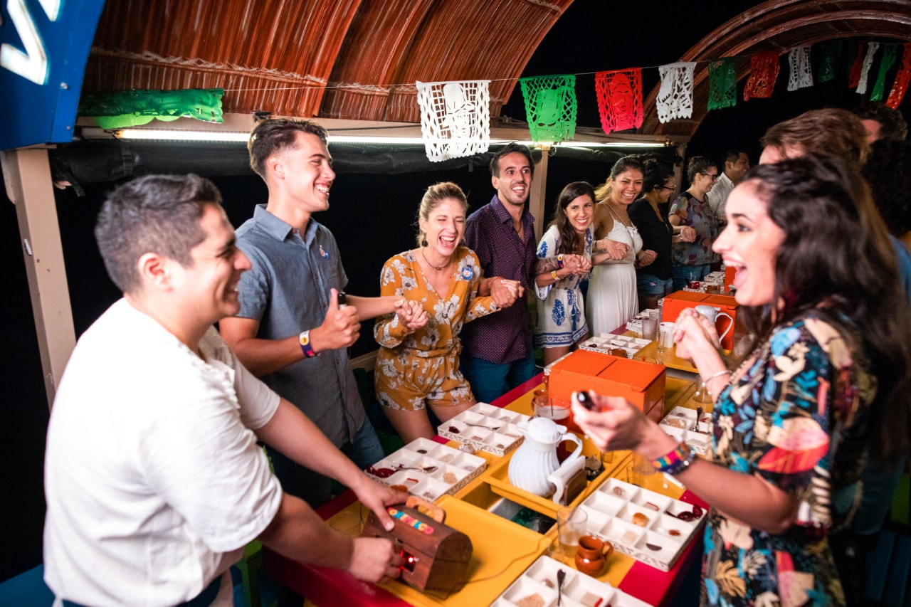 Group of guests laughing and playing games at a colourful table on the Xoximilco fiesta boat