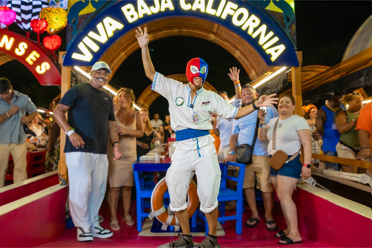 Entertainer in a lucha libre mask posing under the Viva Baja California arch on the Xoximilco trajinera